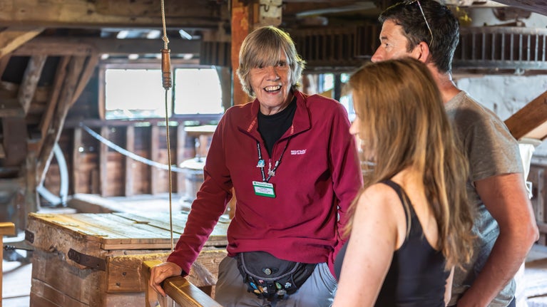 Volunteer guide talking with visitors inside Houghton Mill